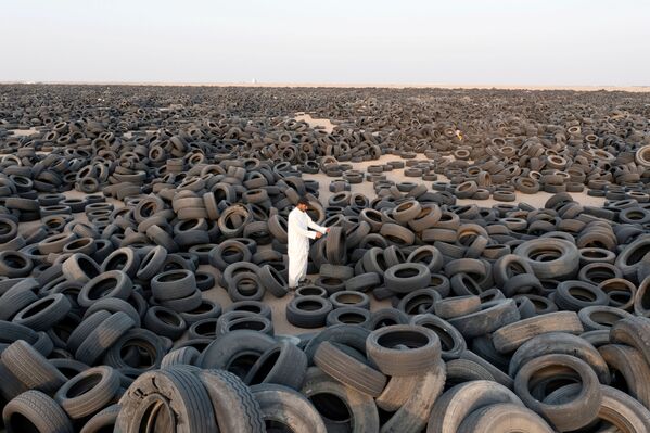 O sírio Ibrahim Kamal em pé entre pneus usados destinados à reciclagem no Kuwait, 4 de setembro de 2021. - Sputnik Brasil
