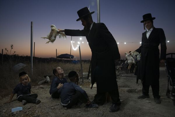 Homem judeu ultra-ortodoxo estende galinha sobre crianças como parte de ritual Kaparot em Beit Shemesh, em Israel, em 13 de setembro de 2021. - Sputnik Brasil