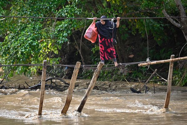 Nas fotos da semana: Mulher atravessa restos de uma ponte na localidade de Malela, no sul de Sulawesi, na Indonésia, em 13 de setembro de 2021. - Sputnik Brasil