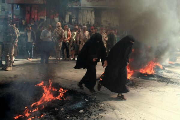 Mulheres correm no fundo de pneus em chamas durante protestos contra a deterioração da situação econômica e a desvalorização da moeda no Iêmen, 27 de setembro de 2021. - Sputnik Brasil