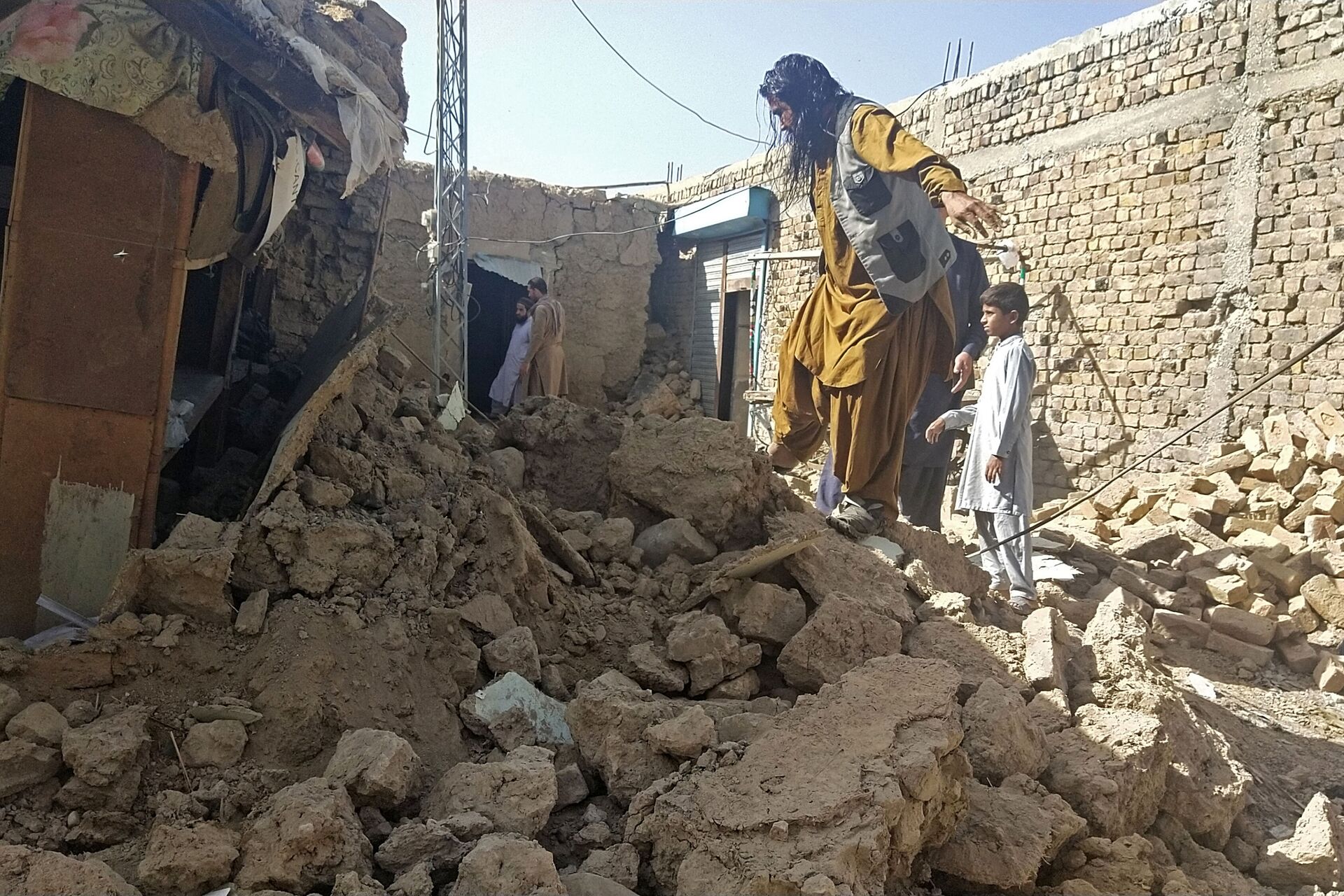 Residentes perto dos escombros de suas casas, que colapsaram na sequência do terremoto no distrito montanhoso de Harnai, Paquistão, 7 de outubro de 2021 - Sputnik Brasil, 1920, 09.11.2021