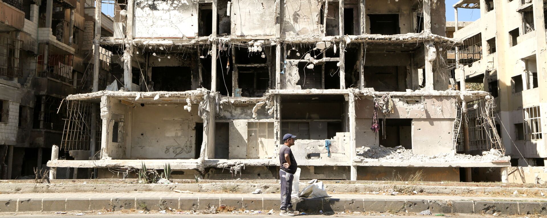 Homem passa por prédio danificado em Homs, Síria, 3 de outubro de 2021 - Sputnik Brasil, 1920, 13.12.2021