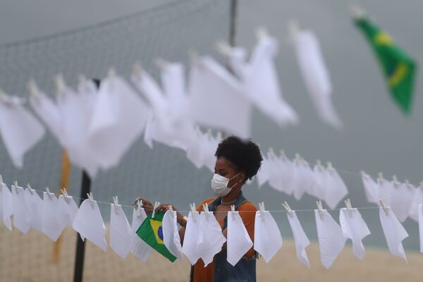 Ativista da organização sem fins lucrativos Rio de Paz, estende lenços brancos junto a bandeira do Brasil, simbolizando as mais de 600 mil mortes em resultado da COVID-19 no país, no Rio de Janeiro, no Brasil, em 8 de outubro de 2021. - Sputnik Brasil