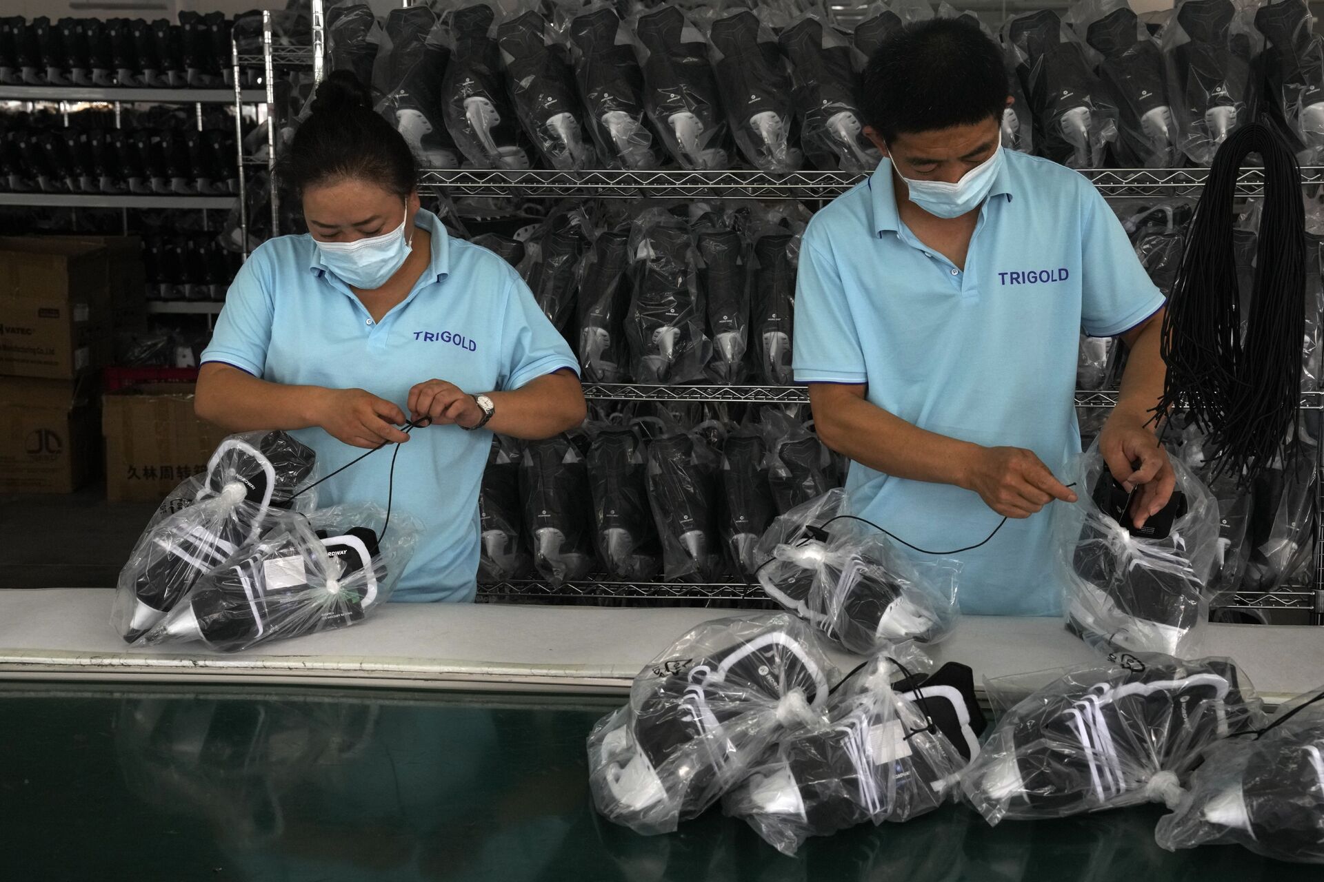 Trabalhadores embalam calçados de patinação no gelo em uma fábrica no parque industrial de equipamentos esportivos de gelo e neve em Zhangjiakou, na província de Hebei, China, 15 de julho de 2021 - Sputnik Brasil, 1920, 15.07.2022