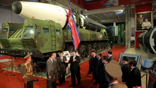 Líder norte-coreano, Kim Jong-un, conversa com oficiais ao lado de armas e veículos militares na exposição Autodefesa-2021, Pyongyang, Coreia do Norte, foto divulgada em 12 de outubro de 2021 - Sputnik Brasil