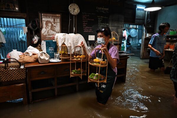 Funcionária de café tailandês inundado Chaopraya Antique segurando sobremesas. - Sputnik Brasil