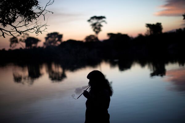Mapulu, uma mulher kamayura, fuma ervas aromáticas durante o ritual fúnebre Kuarup. - Sputnik Brasil