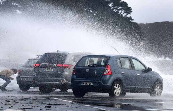 Homem se esconde atrás dos carros enquanto ondas atingem a costa de Le Relecq-Kerhuon, França. - Sputnik Brasil