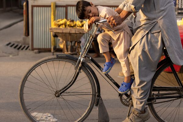 Menino adormecendo em uma bicicleta em Cabul, Afeganistão. - Sputnik Brasil