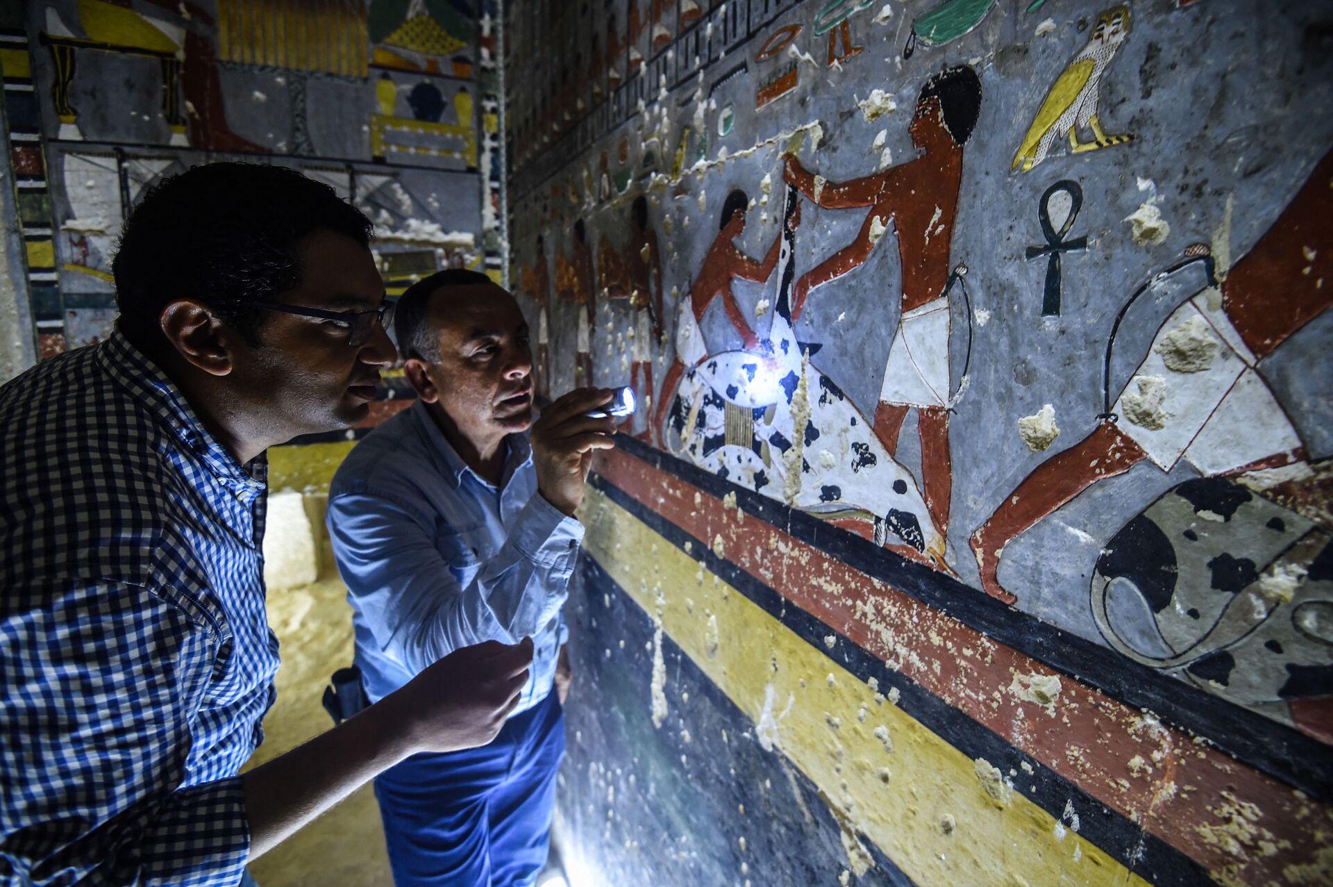 Mohamed Mujahid (à esquerda), chefe da missão egípcia que descobriu o túmulo do antigo nobre egípcio Khuwy, datado da 5ª dinastia (2494-2345 a.C.), inspeciona as paredes internas do túmulo na necrópole de Saqqara, cerca de 35 quilômetros ao sul da capital Cairo, 13 de abril de 2019 - Sputnik Brasil, 1920, 09.11.2021