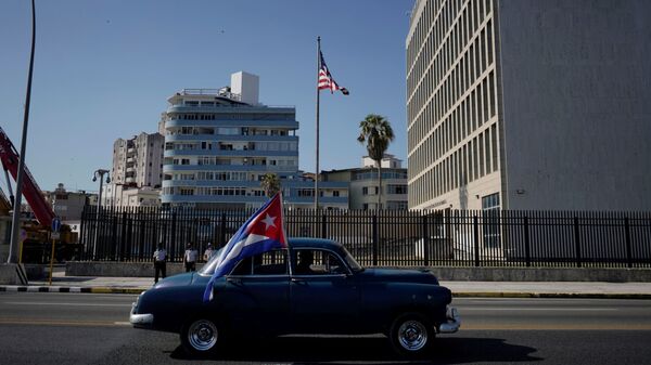 Carro antigo passa pela embaixada dos EUA carregando uma bandeira cubana durante carreata de protesto contra o embargo contra Cuba pelos EUA, Havana, 28 de março de 2021 - Sputnik Brasil