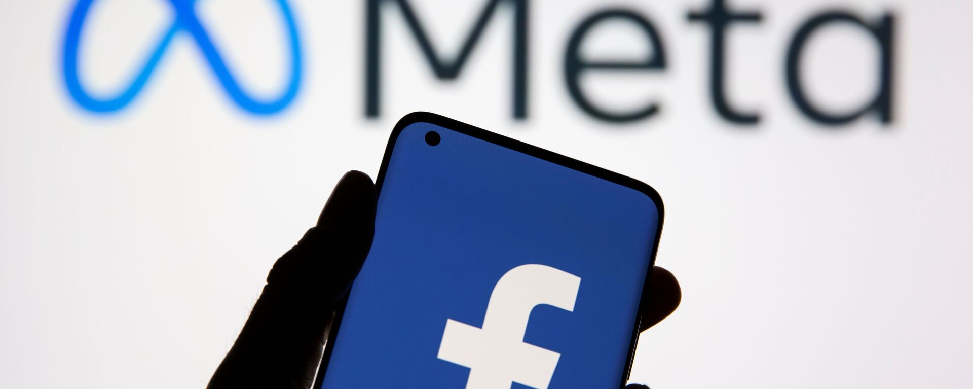 Smartphone com logotipo do Facebook em frente de um logotipo do Meta, novo nome da empresa Facebook, 28 de outubro de 2021 - Sputnik Brasil, 1920, 02.12.2021
