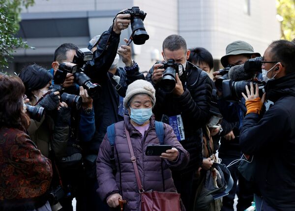 Fotógrafos tiram fotos de mulher assistindo a uma transmissão ao vivo da coletiva de imprensa da princesa japonesa Mako e seu marido Kei Komuro. - Sputnik Brasil
