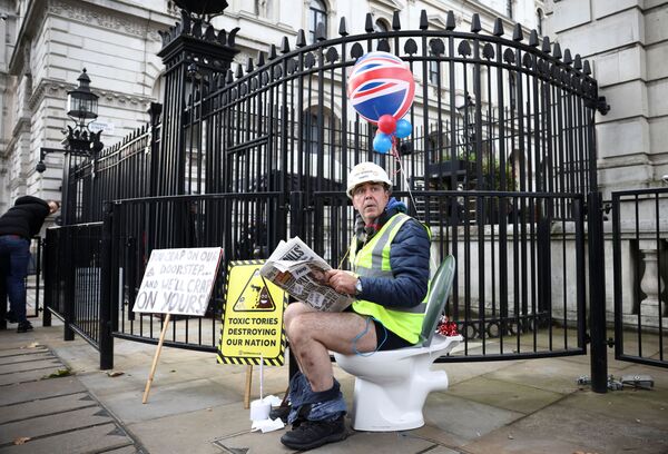 Ativista protesta sentado em uma privada em Downing Street, onde se localiza a residência oficial do primeiro-ministro britânico.  - Sputnik Brasil