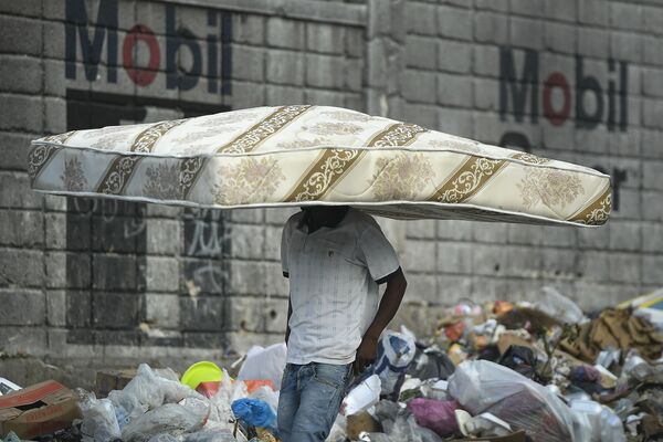 Homem passa na rua com um colchão na cabeça, em Porto Príncipe, Haiti. - Sputnik Brasil