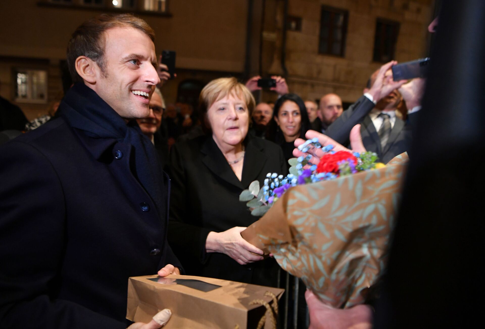 Chanceler alemã, Angela Merkel, e presidente francês, Emmanuel Macron, são presenteados com flores e vinho por moradores de Beaune, França, 3 de novembro de 2021 - Sputnik Brasil, 1920, 09.11.2021