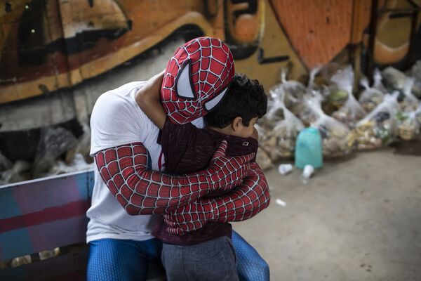 Voluntário fantasiado de Homem-Aranha abraça criança no bairro de Jardim Gramacho, Rio de Janeiro, Brasil, 30 de outubro de 2021. - Sputnik Brasil