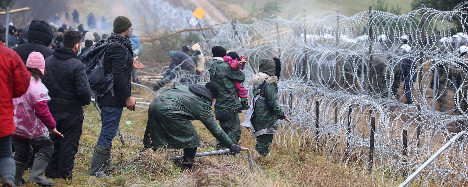 Migrantes se reúnem junto de cerca de arame farpado, com guardas fronteiriços poloneses do outro lado, para tentar cruzar a fronteira com a Polônia na região de Grodno, Belarus, 8 de novembro de 2021 - Sputnik Brasil, 1920, 08.11.2021