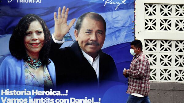 Homem passa por um cartaz que exibe o presidente da Nicarágua Daniel Ortega e a vice-presidente Rosario Murillo antes das eleições presidenciais no país - Sputnik Brasil