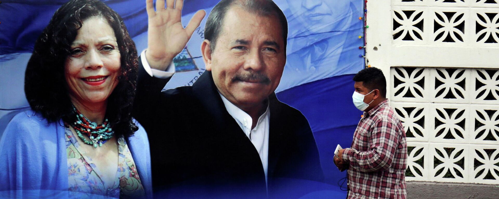Homem passa por um cartaz que exibe o presidente da Nicarágua Daniel Ortega e a vice-presidente Rosario Murillo antes das eleições presidenciais no país - Sputnik Brasil, 1920, 20.11.2021