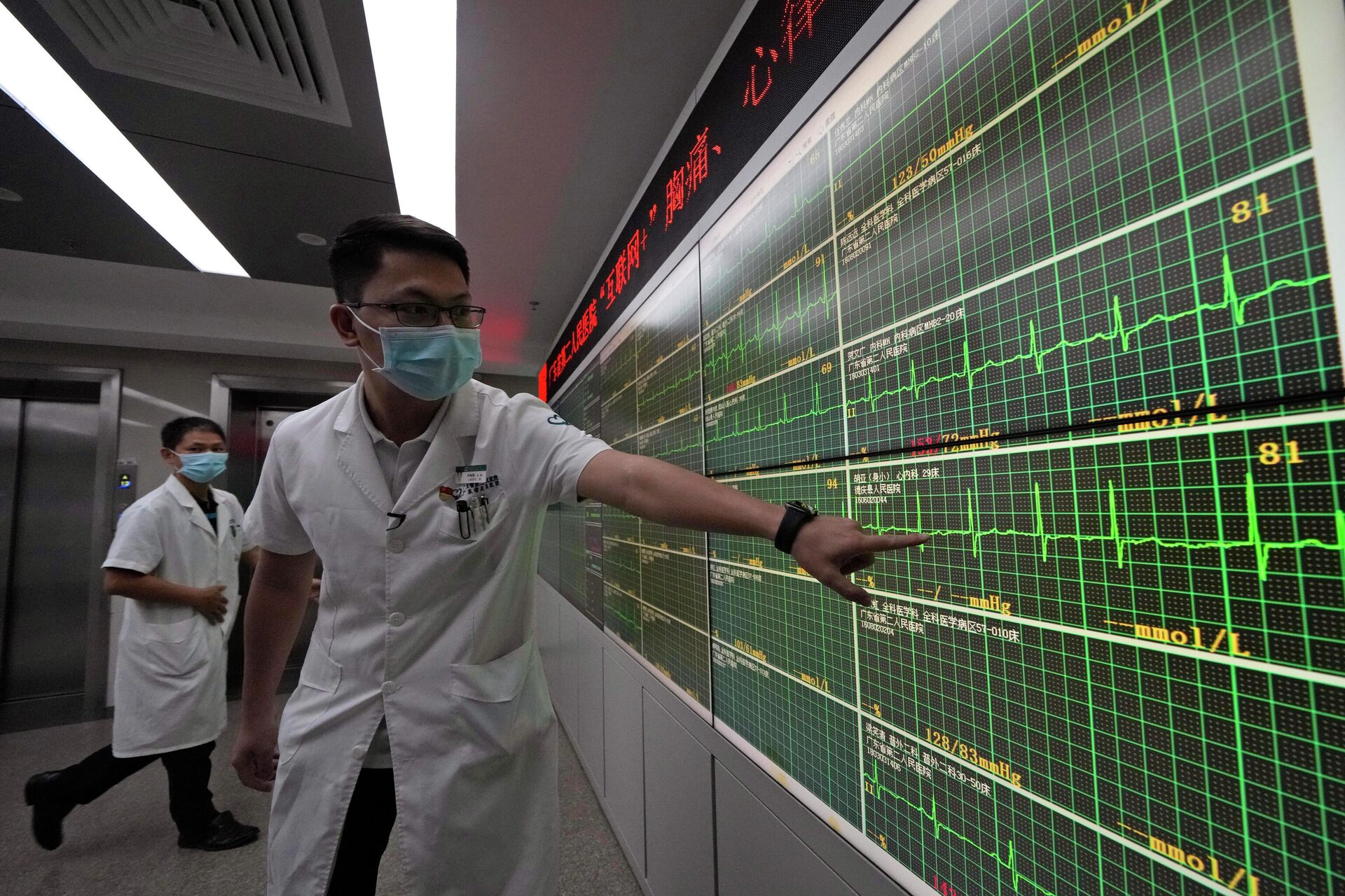 Médico aponta para um eletrocardiograma em tempo real de um paciente exibido em uma placa de um hospital em Guangzhou, China, o qual está usando tecnologias 5G para coletar, transmitir e monitorar mais dados em tempo real 26 de setembro de 2021 - Sputnik Brasil, 1920, 09.11.2021