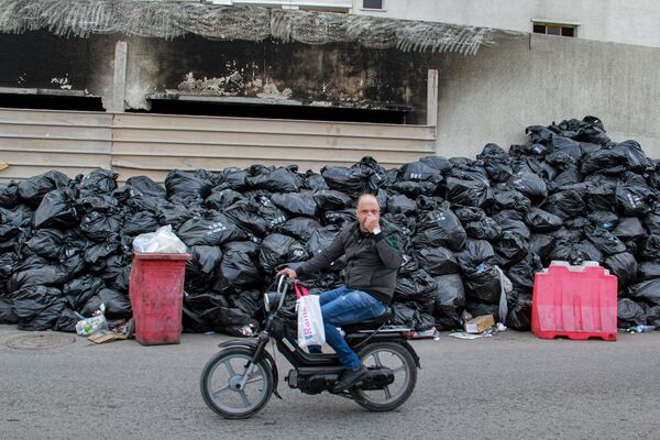 Motociclista passando por monte de sacos com lixo na cidade de Sfax, na Tunísia, em 6 de novembro de 2021. - Sputnik Brasil