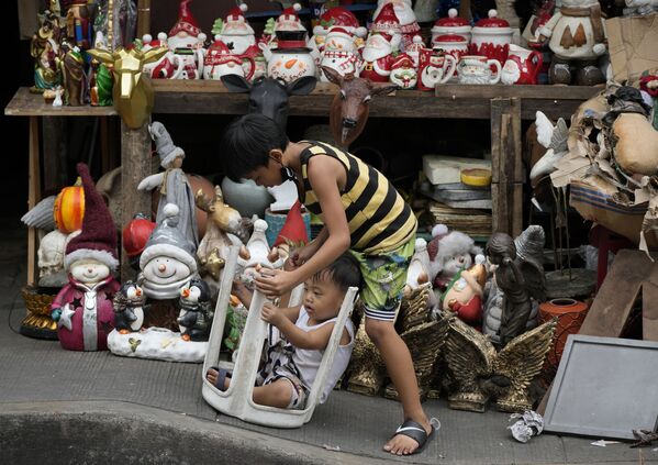 Crianças brincam perto de decorações de Natal vendidas em uma rua na capital filipina de Manila, em 8 de novembro de 2021. - Sputnik Brasil