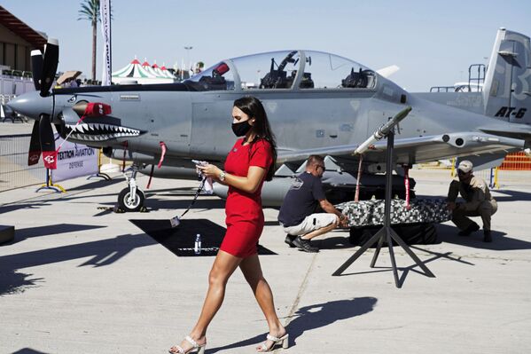 Mulher passa ao lado de aeronave leve de ataque Beechcraft AT-6 Wolverine durante instalação de dispositivo em sua asa, no Show Aéreo de Dubai, Emirados Árabes Unidos, 14 de novembro de 2021 - Sputnik Brasil
