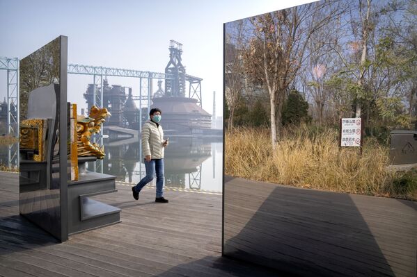 Visitante passa por espelhos em uma instalação artística, refletindo um espaço verde próximo, em Pequim, China, 18 de novembro de 2021. - Sputnik Brasil