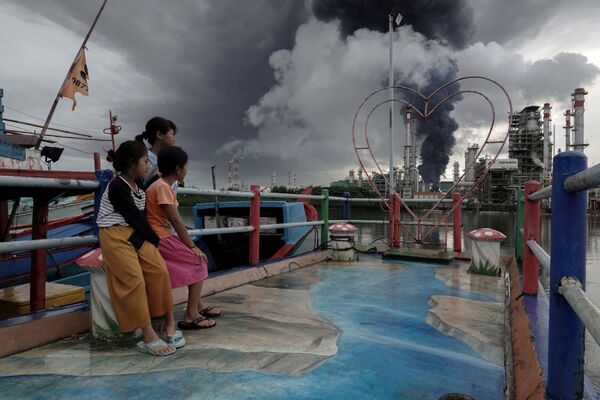 Meninas observam fumaça preta de um incêndio em um depósito de combustível, Indonésia, 14 de novembro de 2021. - Sputnik Brasil