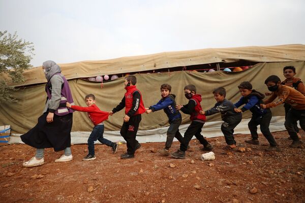 Crianças participam de evento ao ar livre para assinalar o Dia Mundial da Criança no acampamento de Haranbush para sírios deslocados, no norte da província de Idlib, no noroeste da Síria. - Sputnik Brasil