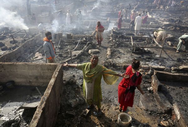 Uma mulher chora enquanto moradores coletam seus pertences em Karachi, no Paquistão, depois de um incêndio que destruiu suas moradias. - Sputnik Brasil