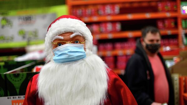 Um comprador passa por uma representação de Papai Noel de máscara contra a COVID-19, em uma loja em Wilmington, em Delaware, nos EUA, em 19 de novembro de 2020 - Sputnik Brasil