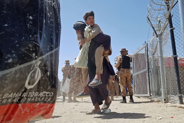 Afegão carrega seu filho no posto de travessia na fronteira entre Afeganistão e Paquistão em Chaman, 13 de agosto de 2021, após o Talibã (organização sob sanções da ONU por atividade terrorista) assumir o controle da cidade fronteiriça. - Sputnik Brasil