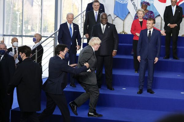 O presidente francês, Emmanuel Macron, sorri enquanto ajuda o primeiro-ministro britânico, Boris Johnson, a subir ao palco durante a cúpula do G20 em Roma, 30 de outubro de 2021. - Sputnik Brasil