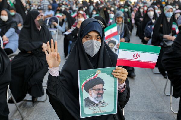 Mulher segura uma foto do novo presidente eleito do Irã, Ebrahim Raisi, enquanto apoiadores celebram sua vitória na capital Teerã, 9 de junho de 2021. - Sputnik Brasil