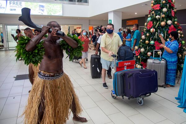 Dançarinos tradicionais dão boas-vindas a passageiros em aeroporto, depois da abertura a viajantes internacionais pela primeira vez desde o início da pandemia da COVID-19, Nadi, Fiji, 1º de dezembro de 2021 - Sputnik Brasil