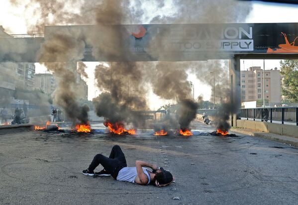 Manifestante deitado em rua bloqueada por pneus ardentes, durante protesto em meio à crise econômica, Beirute, Líbano, 29 de novembro de 2021 - Sputnik Brasil
