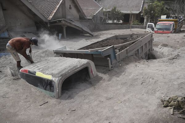 Homem inspeciona caminhão enterrado em cinza no distrito de Lumajang, Indonésia, 5 de dezembro de 2021, após erupção do vulcão Semeru - Sputnik Brasil