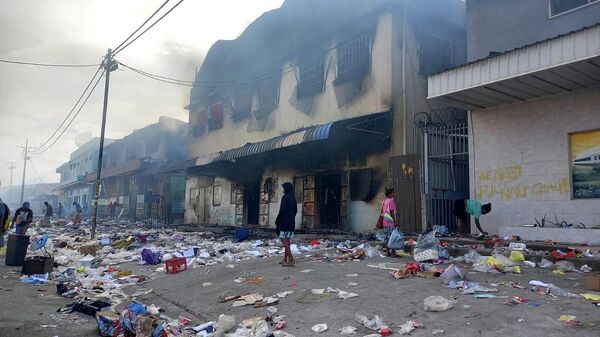Pessoas em meio a detritos de prédio queimado após dias de desacatos em Honiara, Ilhas Salomão, 26 de novembro de 2021. - Sputnik Brasil