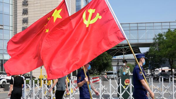 Segurança carregam bandeiras do Partido Comunista e da China durante evento em Pequim, no dia 2 de setembro de 2021 - Sputnik Brasil