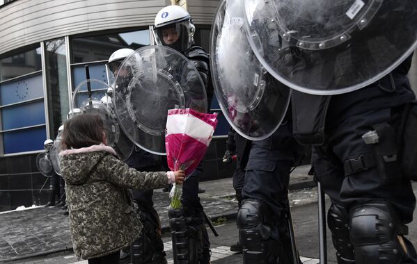 Menina oferece flores a agentes da polícia de choque durante protesto contra as medidas restritivas da COVID-19 em Bruxelas, Bélgica. - Sputnik Brasil