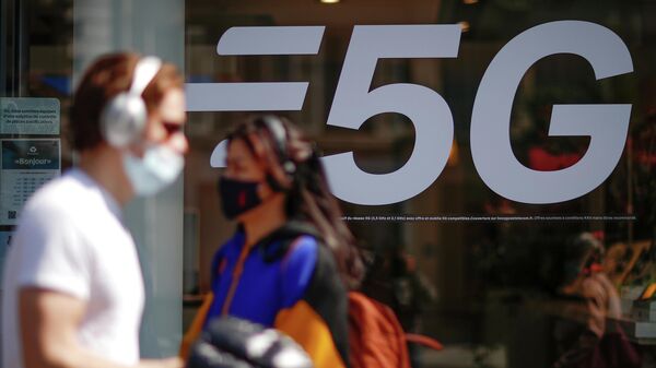 Pessoas com máscaras faciais protetoras passam ao lado de placa de rede 5G em loja de celulares em Paris, França, 22 de abril de 2021 - Sputnik Brasil