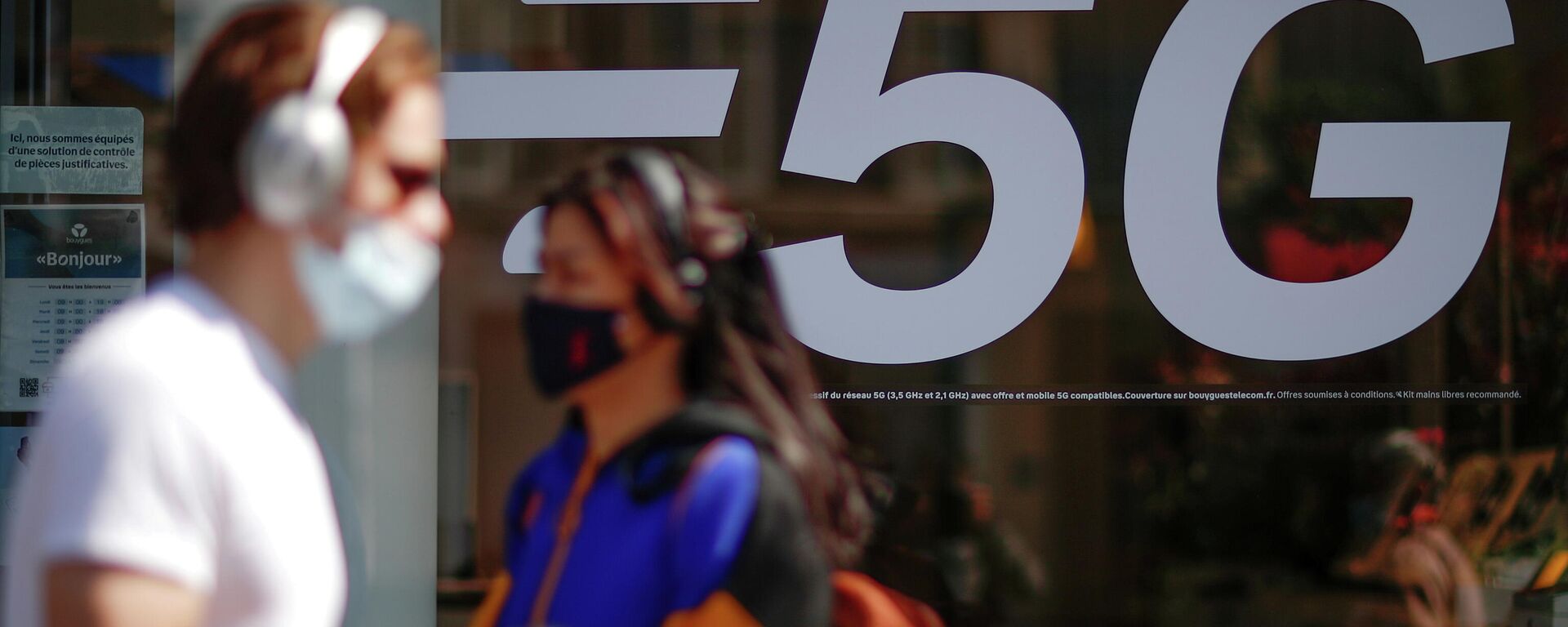 Pessoas com máscaras faciais protetoras passam ao lado de placa de rede 5G em loja de celulares em Paris, França, 22 de abril de 2021 - Sputnik Brasil, 1920, 13.12.2021