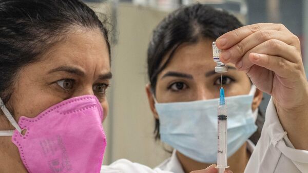 Em Porto Alegre, agentes de saúde preparam uma dose de vacina contra a COVID-19 em posto de vacinação, em 13 de dezembro de 2021 - Sputnik Brasil