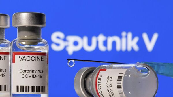 Frascos de Vacina de coronavírus COVID-19 e seringa com logotipo da Sputnik V no fundo em 11  de dezembro de 2021 - Sputnik Brasil