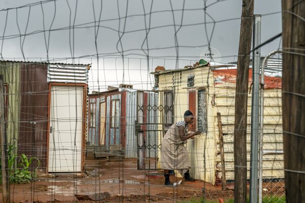 Moradora do assentamento de Vlak Fontein, nos arredores de Joanesburgo, África do Sul, fecha sua janela durante uma tempestade. - Sputnik Brasil