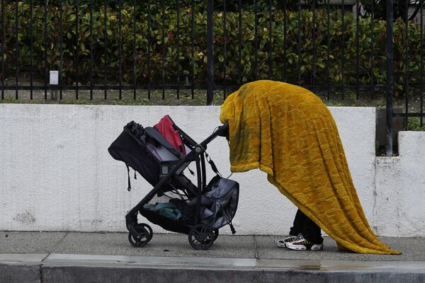 Um morador de rua se protege da chuva sob uma cobertura no centro de Los Angeles, EUA. - Sputnik Brasil