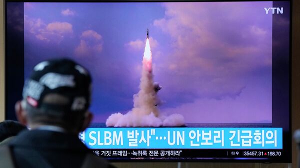 Um homem assiste a uma TV que mostra a imagem do míssil balístico da Coreia do Norte lançado de um submarino durante um programa de notícias na Estação Ferroviária de Seul, na Coreia do Sul, quarta-feira, 20 de outubro de 2021 - Sputnik Brasil
