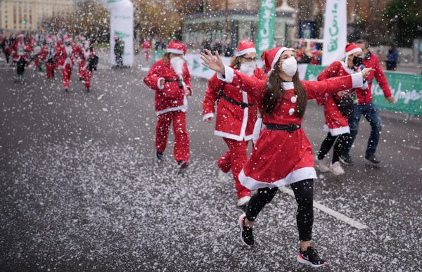 Pessoas fantasiadas de Papai Noel participam de corrida de caridade para coletar dinheiro e ajudar as vítimas da erupção do vulcão Cumbre Vieja, Madri, Espanha, 19 de dezembro de 2021. - Sputnik Brasil